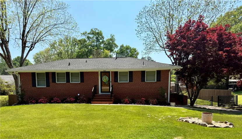 A classic brick exterior offers timeless curb appeal with a well-maintained lawn and vibrant landscaping.