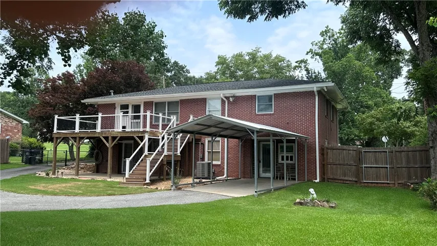 A well-maintained brick residence offers a spacious deck and convenient carport, set amidst a verdant lawn.