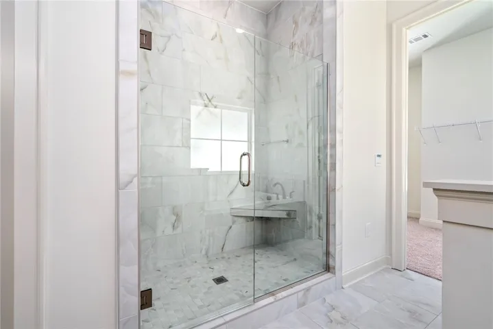 This spacious bathroom offers a walk-in shower with elegant tile work and ample light.