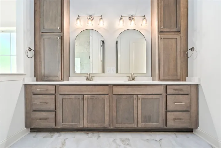 This spacious bathroom features a double vanity and ample storage with elegant fixtures.