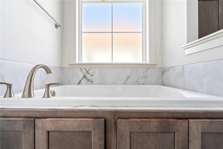 Relax in this inviting tub, featuring a beautiful tile surround and window views.