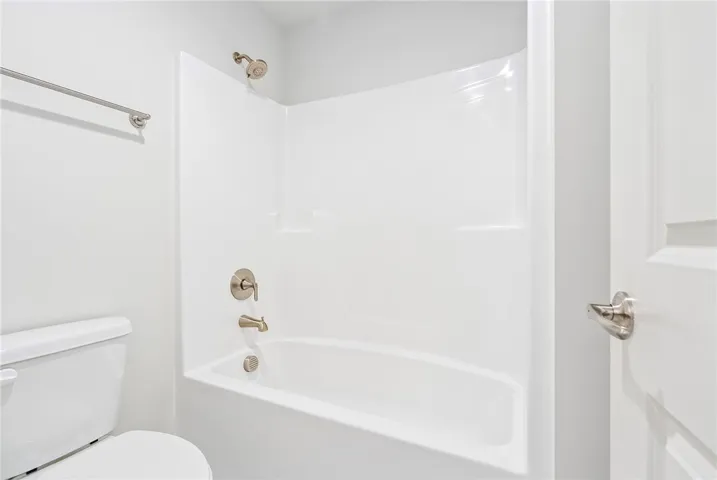 This bathroom features a sleek, modern tub and shower combination with clean white finishes.