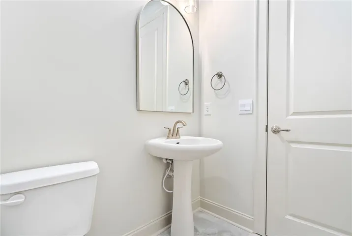 This bright bathroom features a pedestal sink and modern fixtures for comfortable living.
