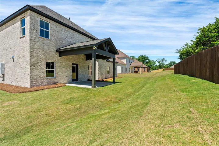 This spacious backyard offers a covered patio and verdant lawn, ideal for outdoor enjoyment.