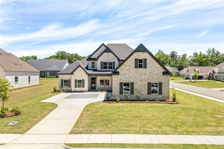 This charming home features a brick exterior and a well-maintained lawn with mature trees.