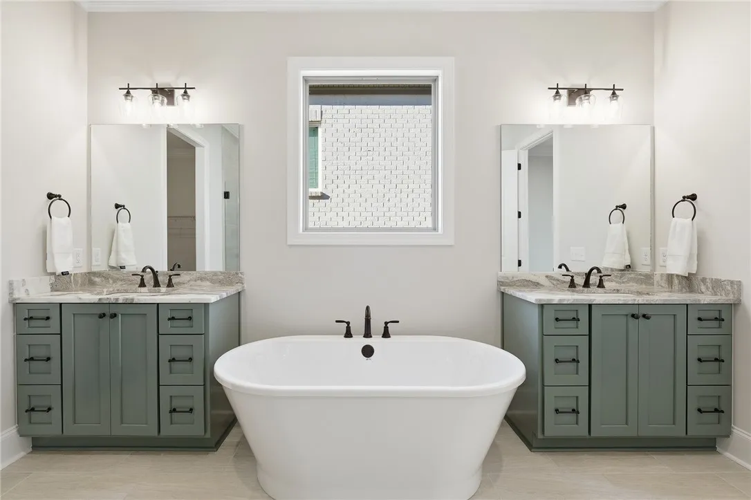 The primary bath features a garden tub, two vanities, a zero-entry, frameless shower, linen closet, water closet, & massive closet.
