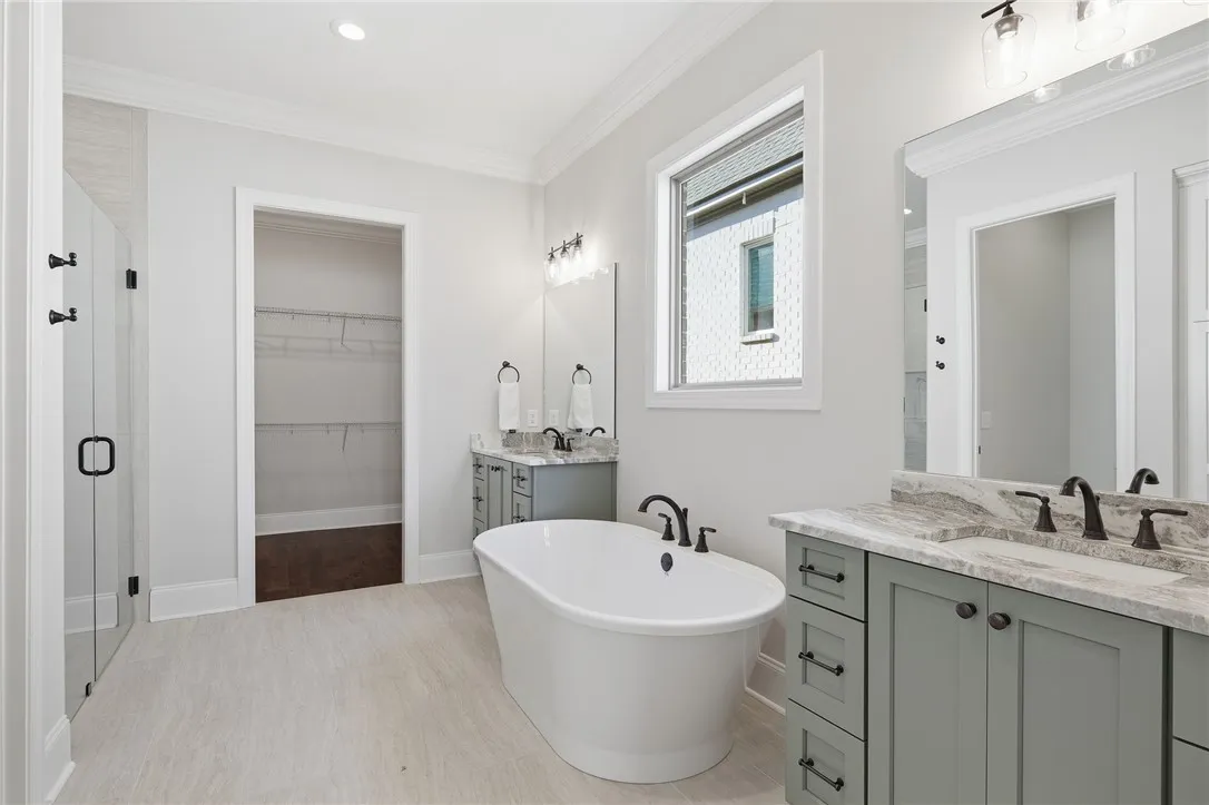 The primary bath offers linen storage in a tasteful built-in tucked behind the door.