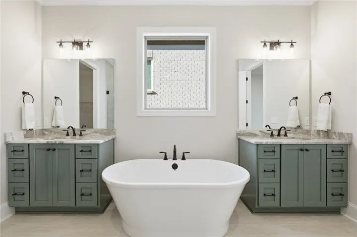 The primary bath features a garden tub, two vanities, a zero-entry, frameless shower, linen closet, water closet, & massive closet.