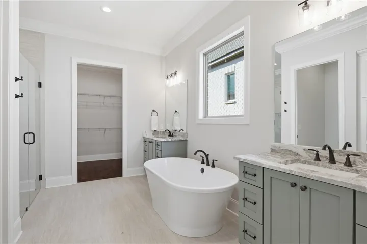 The primary bath offers linen storage in a tasteful built-in tucked behind the door.