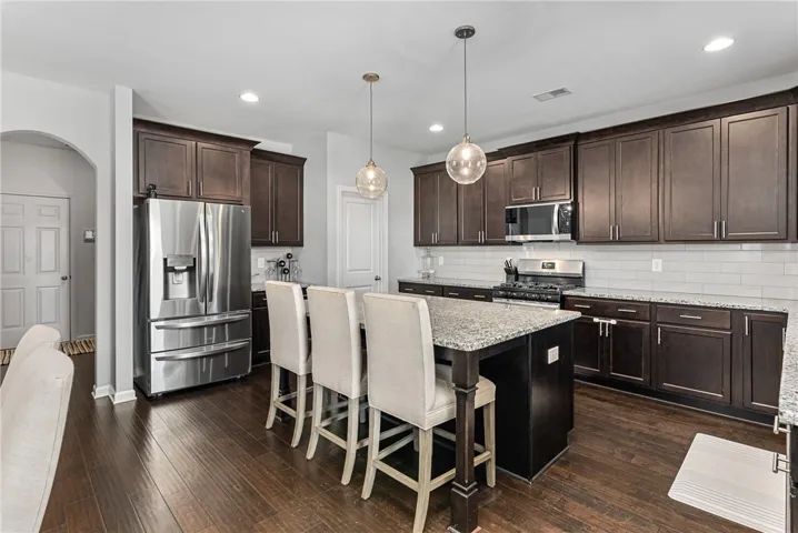 This chef-inspired culinary space features rich cabinetry, granite countertops, and modern pendant lighting over a convenient island.