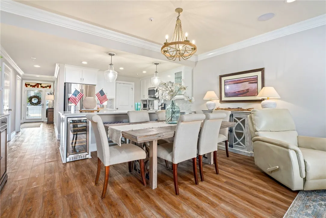 An inviting dining area flows seamlessly into the kitchen, showcasing rich wood flooring and crown molding throughout.
