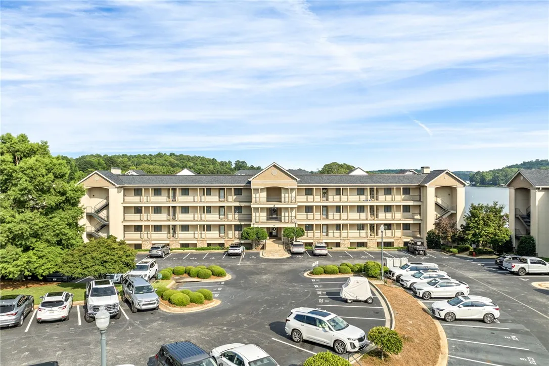 A resort-style condominium building with lake proximity offers ample parking and lush landscaping.