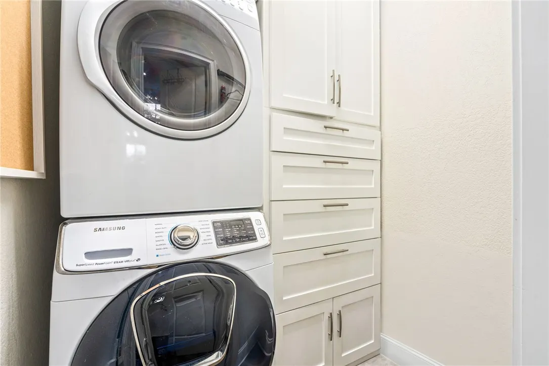 A well-organized laundry area offers a stackable washer and dryer alongside ample built-in storage cabinets.