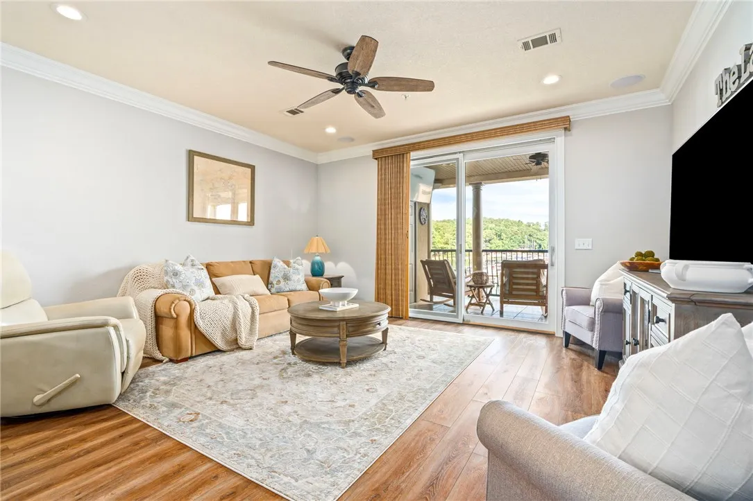 Hardwood flooring and crown molding frame a sun-filled living area opening to an outdoor deck.