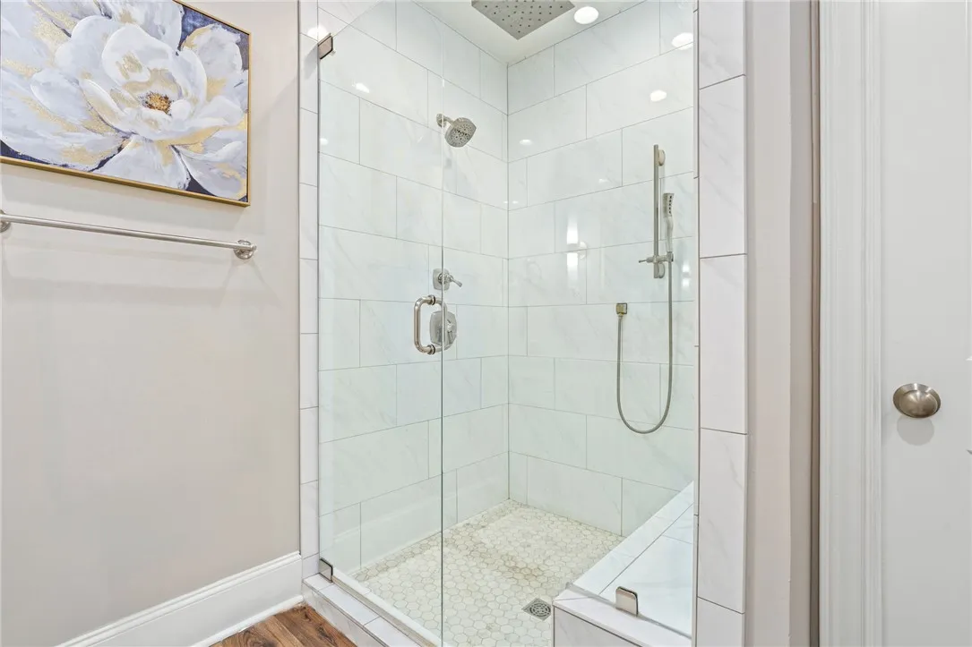 A sleek, contemporary walk-in shower features white subway tile walls and a hexagonal tiled floor.