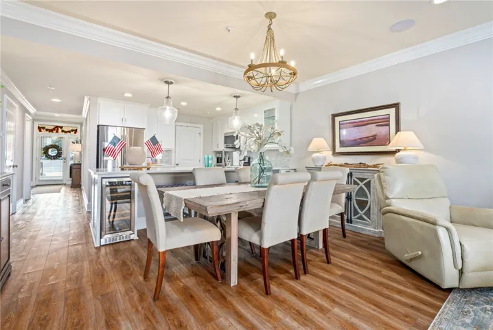 An inviting dining area flows seamlessly into the kitchen, showcasing rich wood flooring and crown molding throughout.