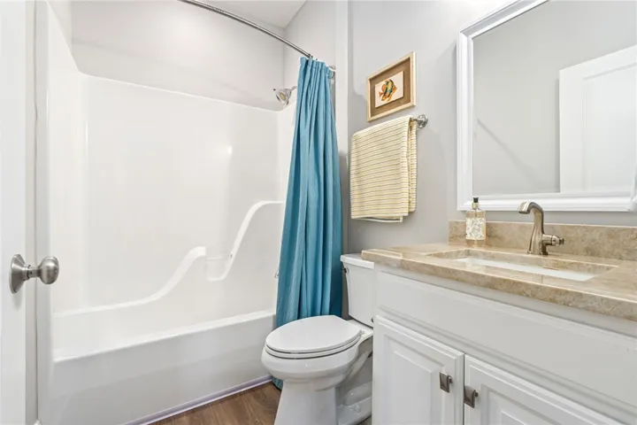 A well-appointed bath features a combined tub and shower unit, complemented by a vanity with a stone countertop.