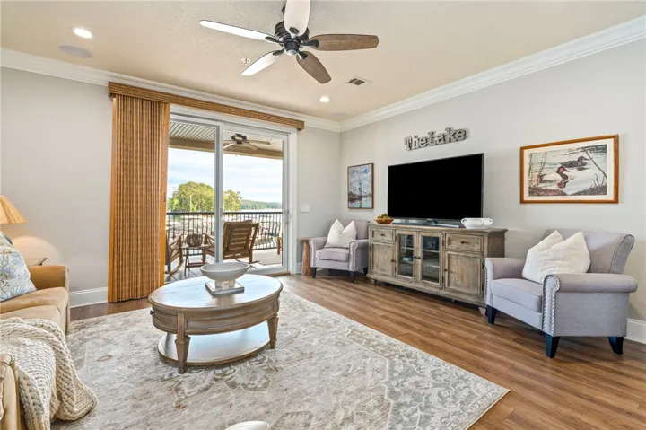 Step into a sun-filled living space with rich hardwood flooring and a broad patio offering panoramic water views.