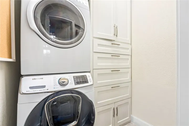 A well-organized laundry area offers a stackable washer and dryer alongside ample built-in storage cabinets.