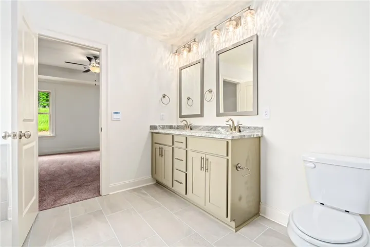 Dual vanity with elegant granite counters and a spacious floor plan define this primary bathroom.