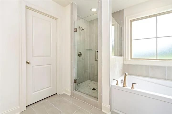 An inviting full bathroom showcases a glass-enclosed shower, a generous soaking tub, and durable tile flooring.
