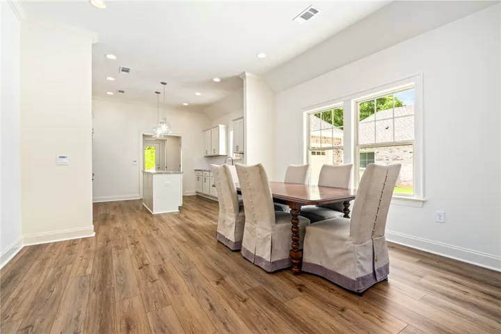 Hardwood floors and a crystal chandelier illuminate this inviting dining space, ideal for entertaining.
