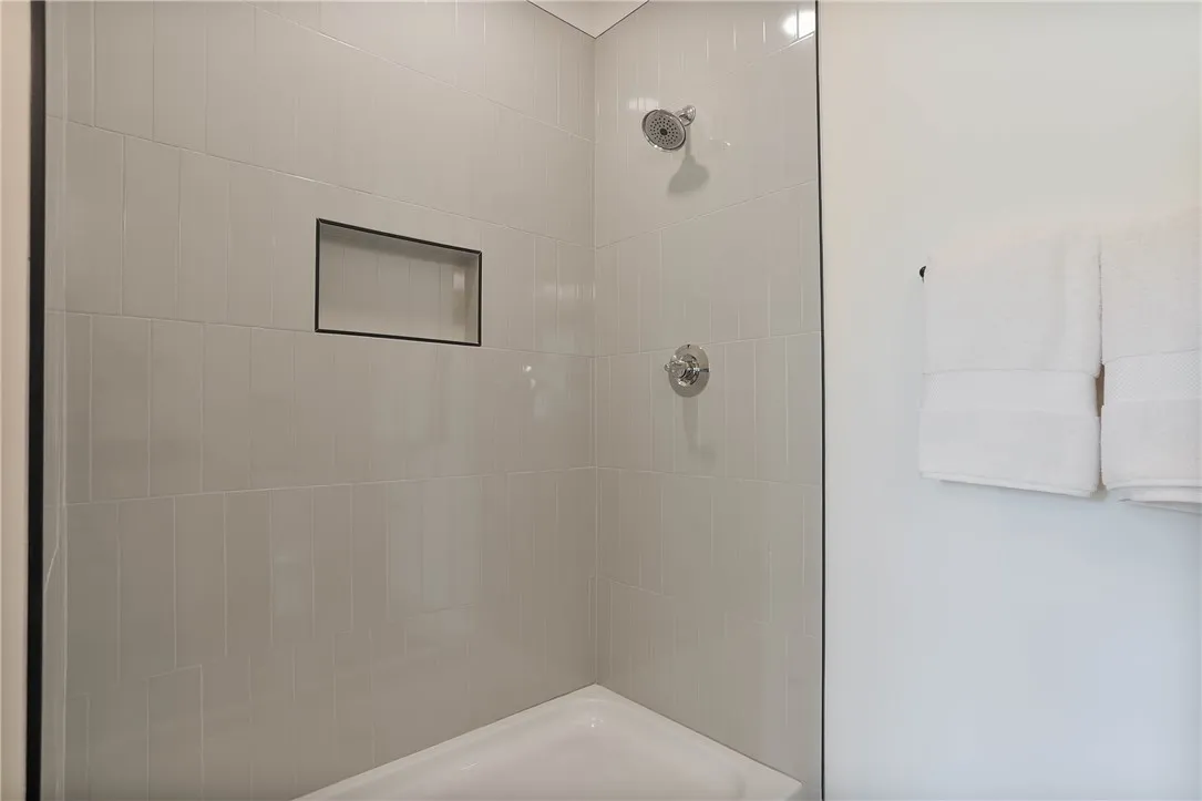 A well-appointed shower with modern tile and built-in shelving.