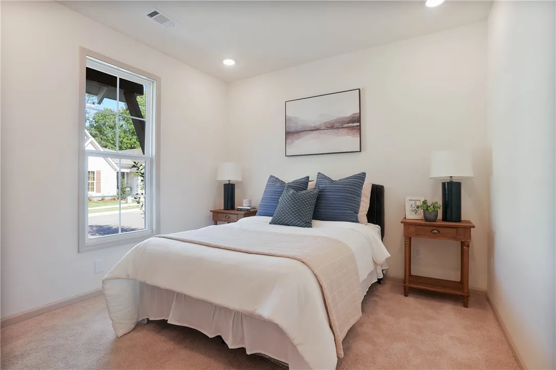 Well-lit and tranquil, this bedroom provides a peaceful retreat with soft carpeting and a view of the quiet neighborhood.