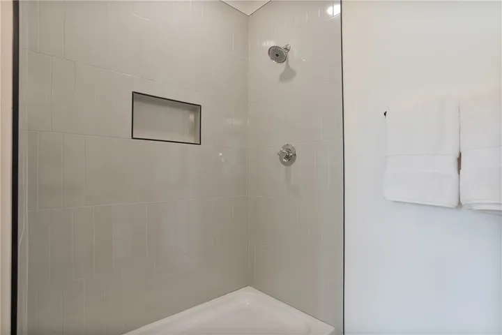 A well-appointed shower with modern tile and built-in shelving.