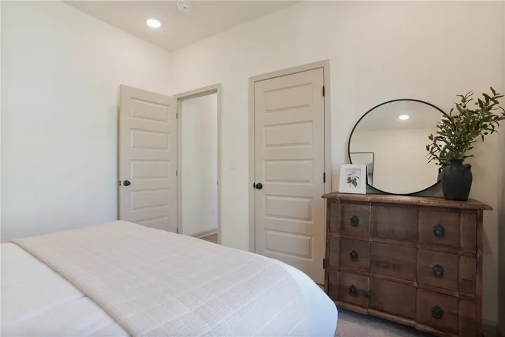 A well-lit bedroom with two doors and a classic dresser, offering functional living space.