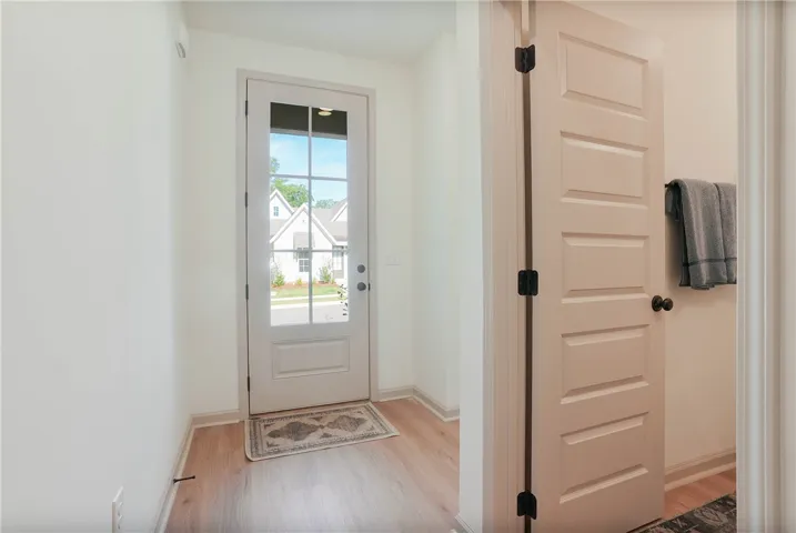 A welcoming entry features natural wood flooring and a bright glass-paneled door.
