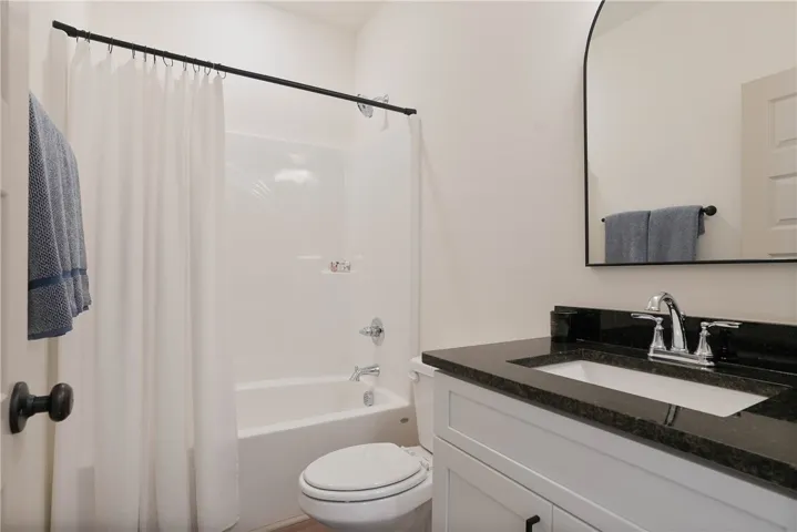 A well-appointed bathroom features a dark granite-topped vanity and a clean, functional tub-shower combination.