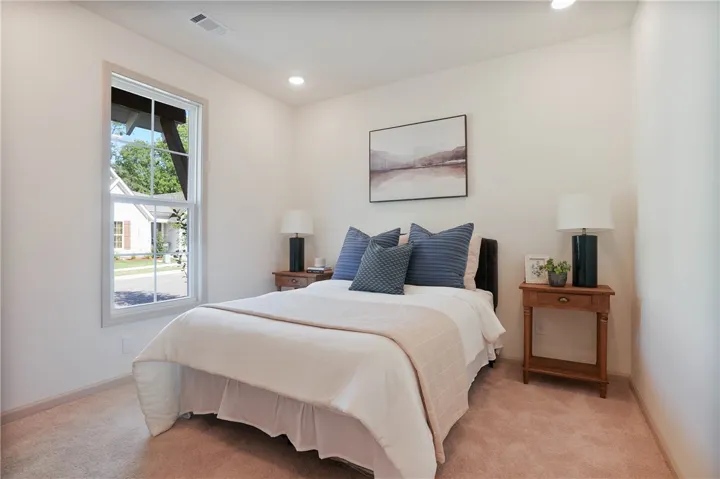 Well-lit and tranquil, this bedroom provides a peaceful retreat with soft carpeting and a view of the quiet neighborhood.