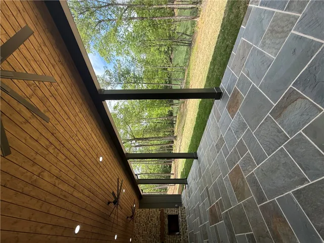 This inviting patio area features durable stone tile flooring and exposed wood ceiling details.