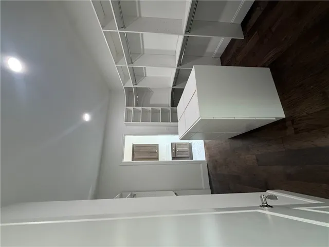 This spacious closet features ample storage solutions and rich hardwood flooring.