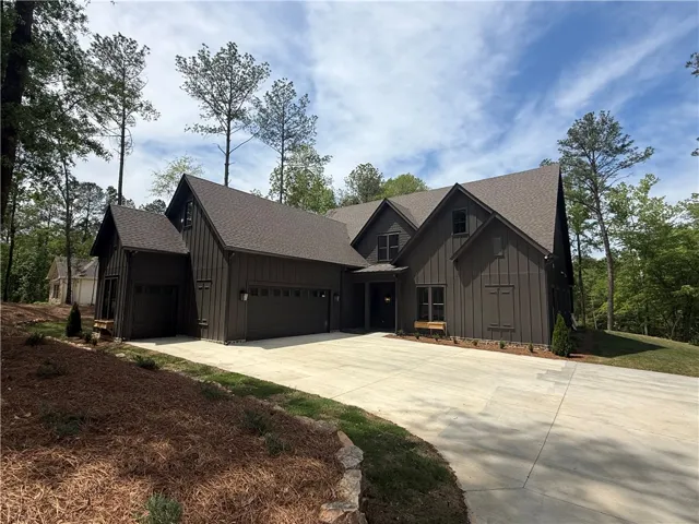 This newly constructed home features a wide driveway and natural surroundings.