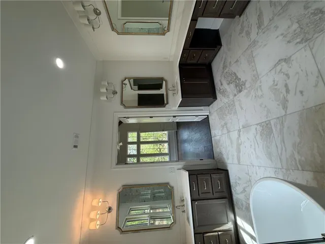 This primary bathroom features a freestanding tub and ample vanity space with elegant tile flooring.