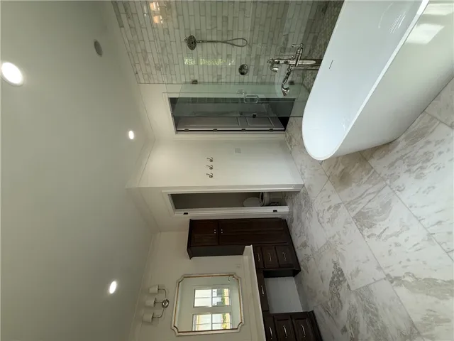 This serene bathroom offers a luxurious soaking tub, a spacious glass-enclosed shower, and elegant tile flooring.