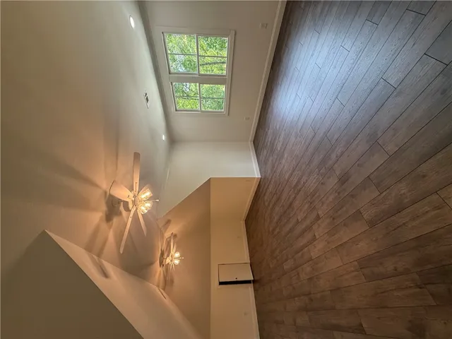 This living space features warm wood flooring and ample natural light from high windows.