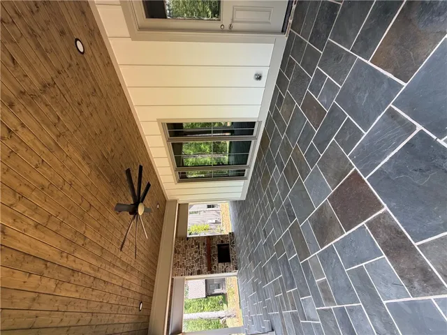 An inviting outdoor living space features sophisticated flooring and a warm wood ceiling.