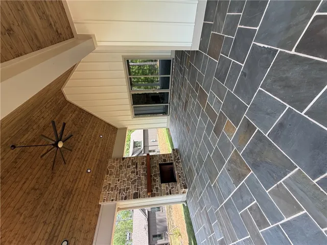 This inviting outdoor living area features a stone fireplace and elegant tile flooring.