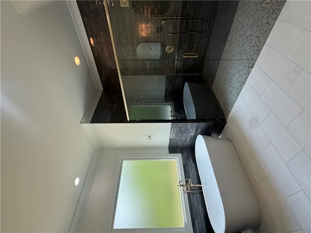 This serene bathroom offers a luxurious soaking tub and a spacious, glass-enclosed shower.
