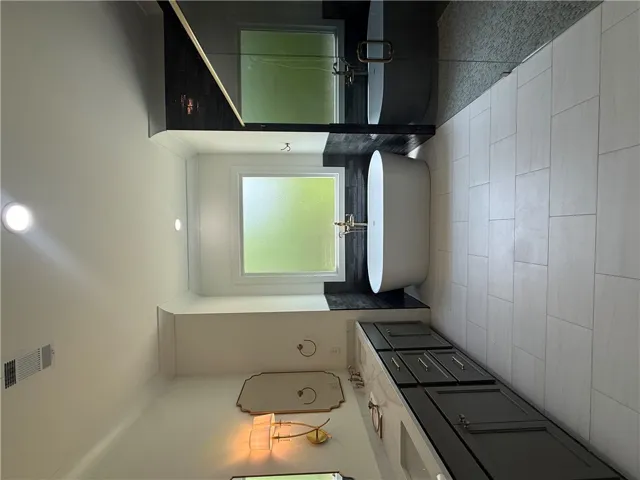 This serene bathing area features sleek surfaces, modern fixtures, and ample natural light.