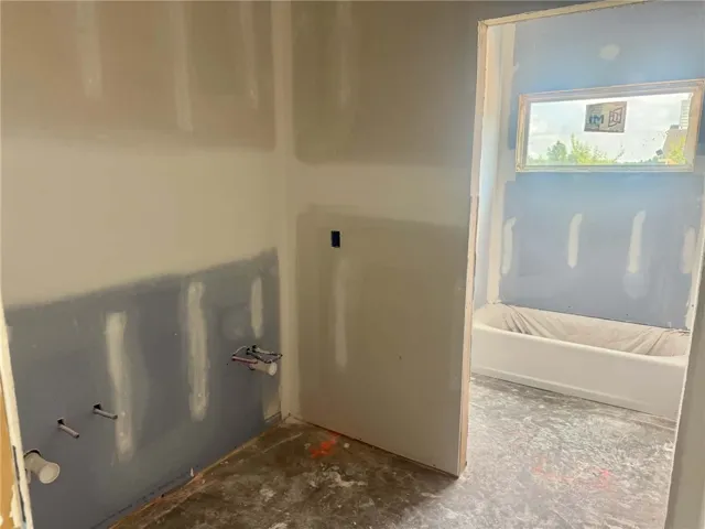 Under-construction bathroom space with a built-in tub and plumbing for a future vanity.