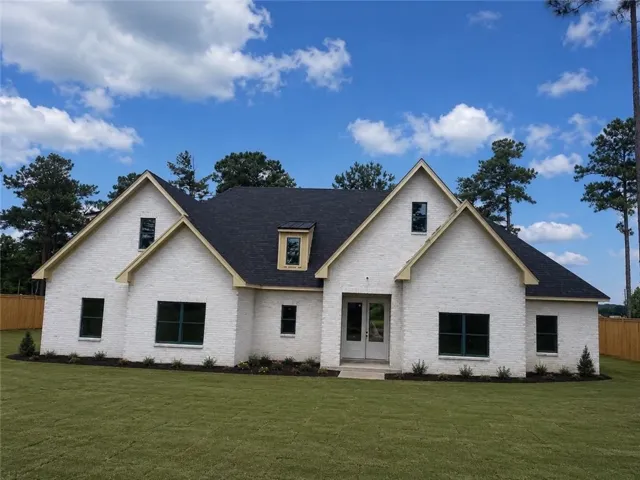 A striking white brick residence with contrasting dark roof and verdant lawn offers superb curb appeal.