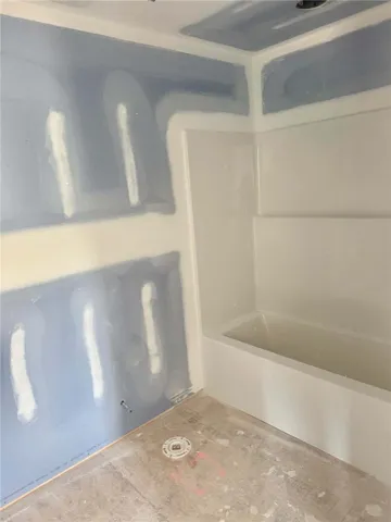 A new bathtub enclosure awaits finishing touches in a developing bathroom space.