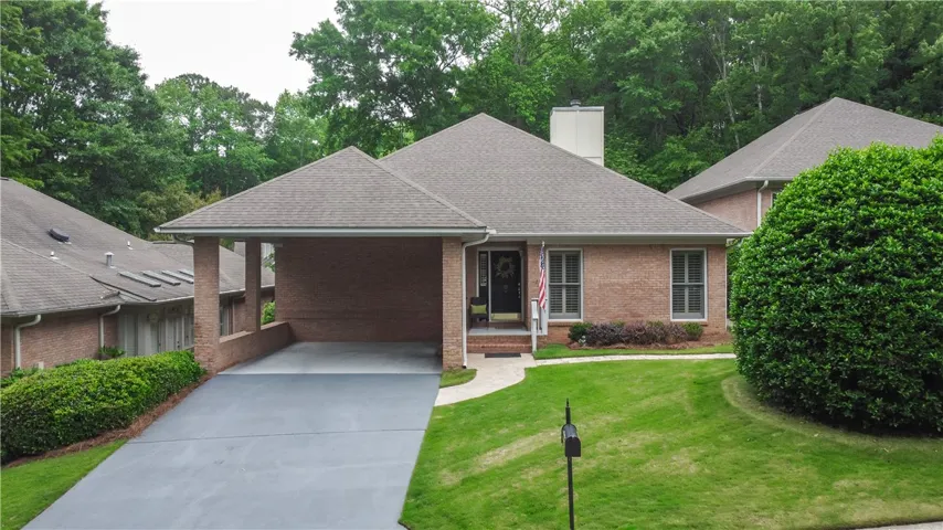This charming brick residence offers a welcoming facade with lush landscaping and a convenient covered carport.
