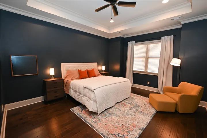 Large primary bedroom with high ceiling, and hardwood floors.