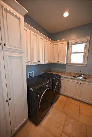The laundry room has ample storage space and a sink.