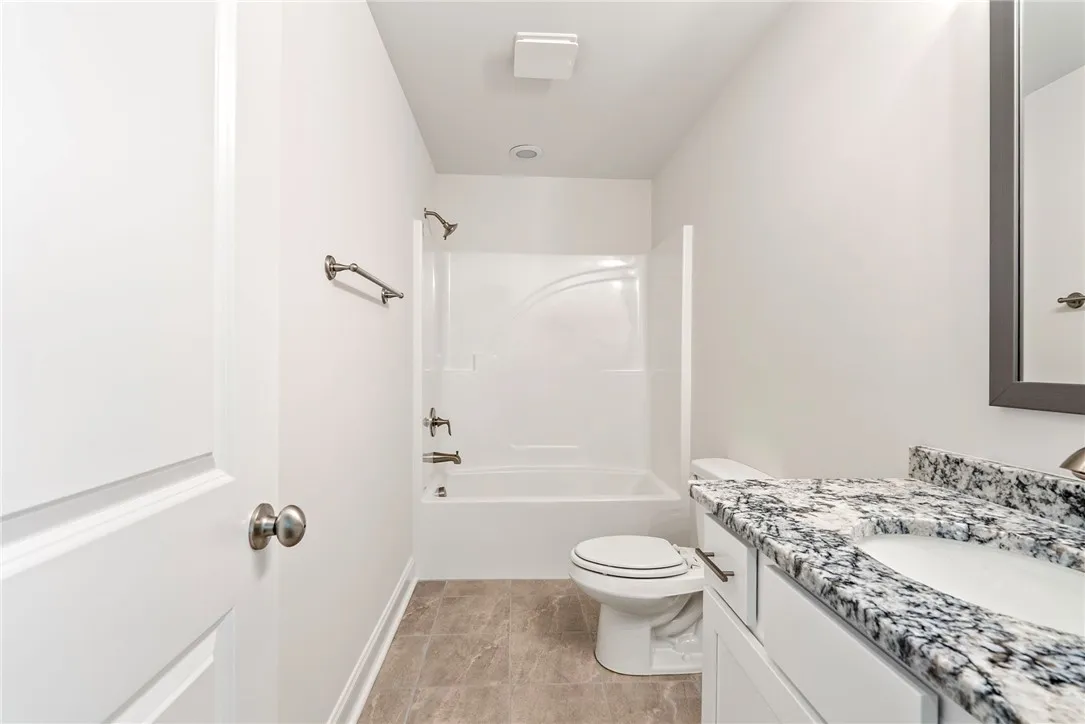 A well-appointed bathroom features a combined tub and shower, alongside a vanity with a granite countertop.
